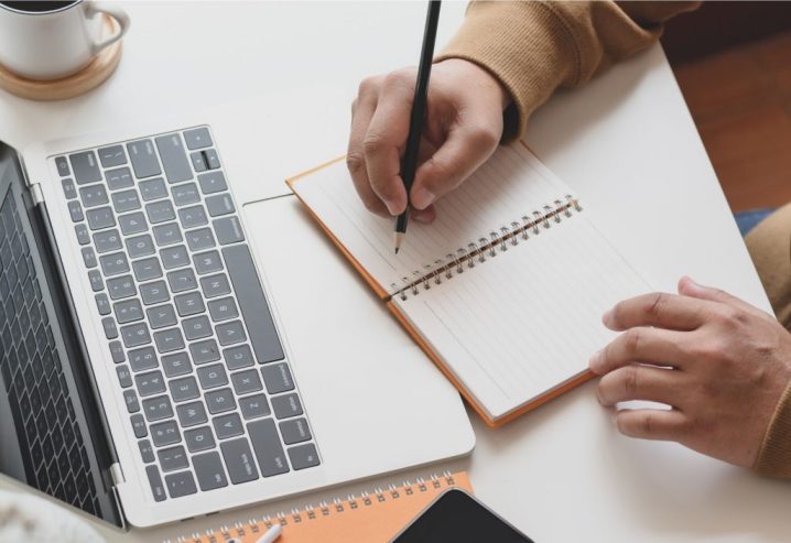 écrire sur un cahier devant un ordinateur